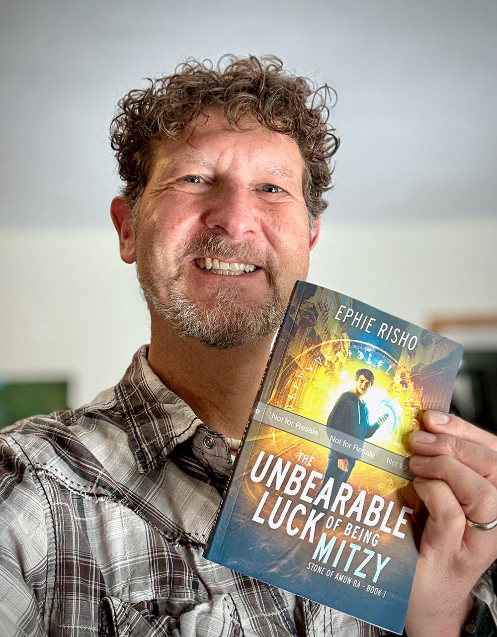 Ephie holding an advance copy of The Unbearable Luck of Being Mitzy, Book 1 of Stone of Amun-Ra